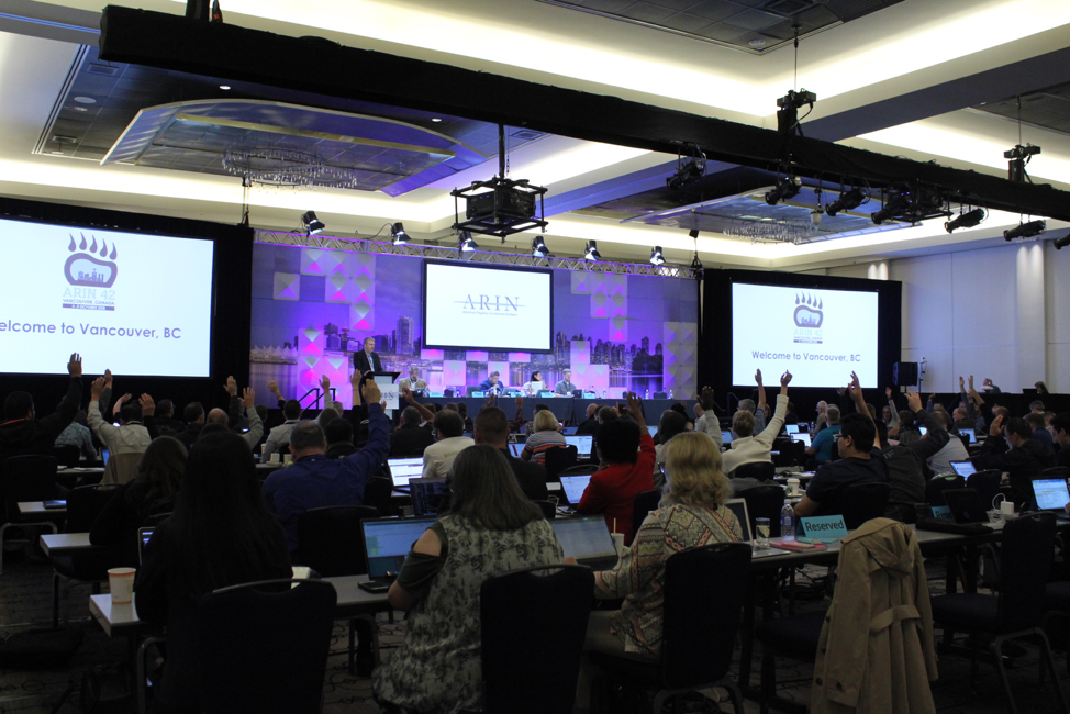 Members raise hands at the meeting.